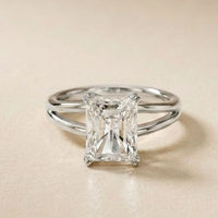Diamond ring with emerald-cut gemstone on a beige background White