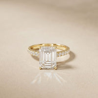 Gold ring with a large diamond and smaller diamonds on a beige background Gold
