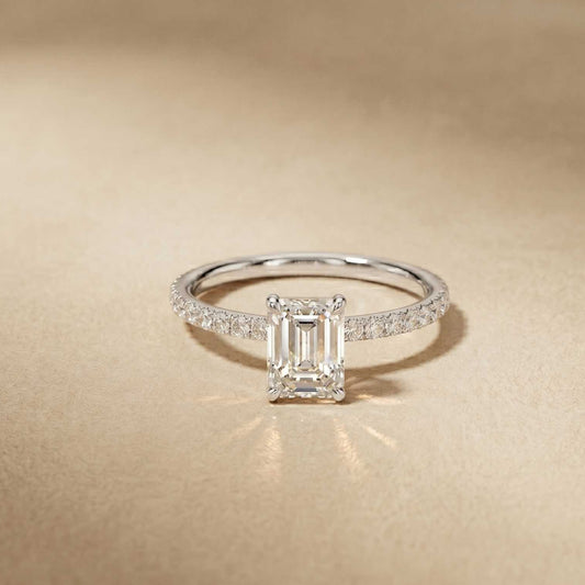 Diamond ring with emerald-cut center stone on a beige background