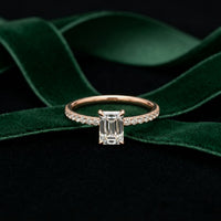 Diamond ring with emerald-cut center stone on green velvet ribbon White