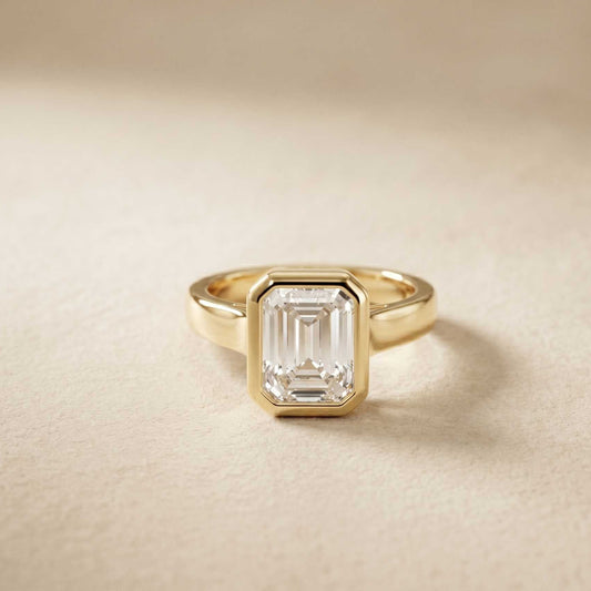 Gold ring with a rectangular diamond on a beige background