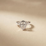 Diamond ring with a pear-shaped gemstone on a beige background White