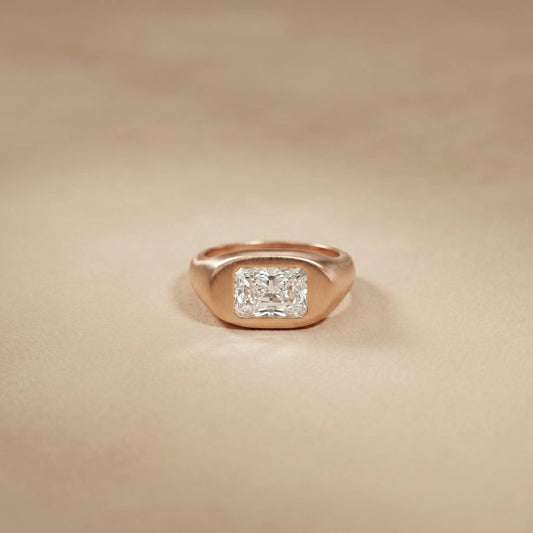 Rose gold ring with a diamond on a beige background