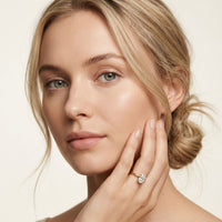 Woman with a diamond ring on her finger against a neutral background Gold