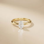 Gold ring with a pear-shaped diamond on a beige background Gold