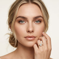 Woman wearing a diamond ring on a plain background Gold