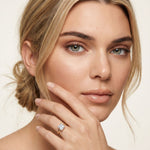Woman wearing a diamond ring on her finger against a neutral background Gold