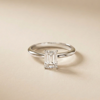 Diamond ring with emerald-cut gemstone on a beige background White