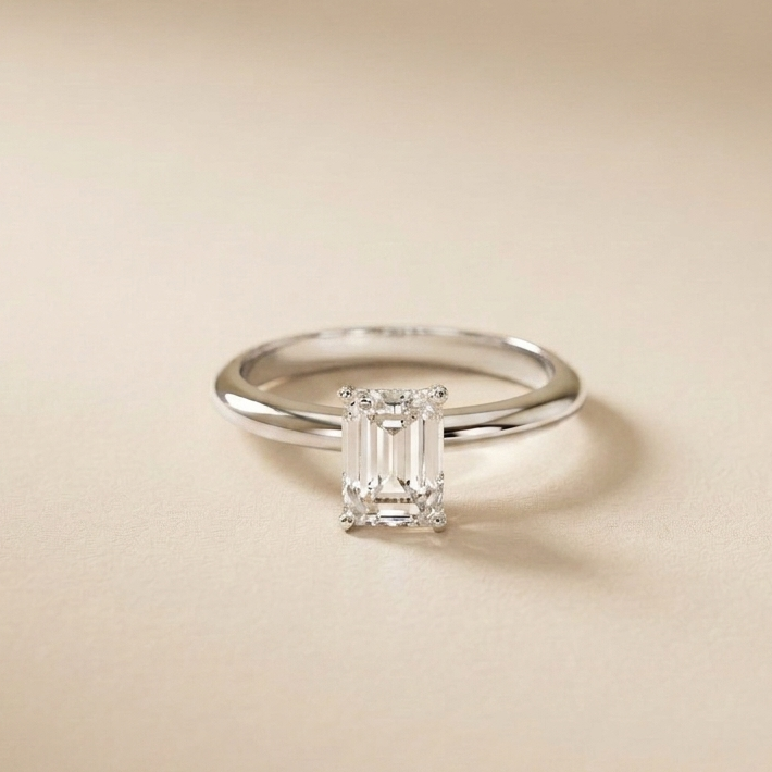 Diamond ring with emerald-cut gemstone on a beige background White