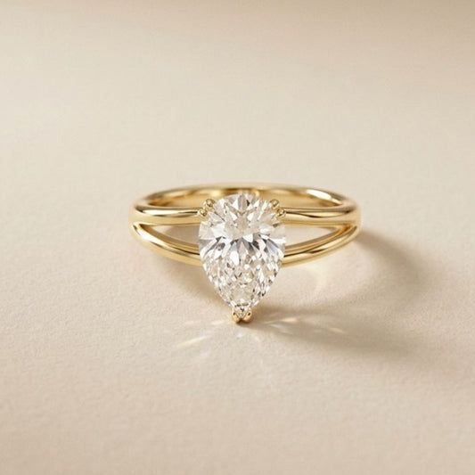 Gold ring with a pear-shaped Lab Grown diamond on a beige background