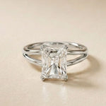 Diamond ring with emerald-cut gemstone on a beige background White