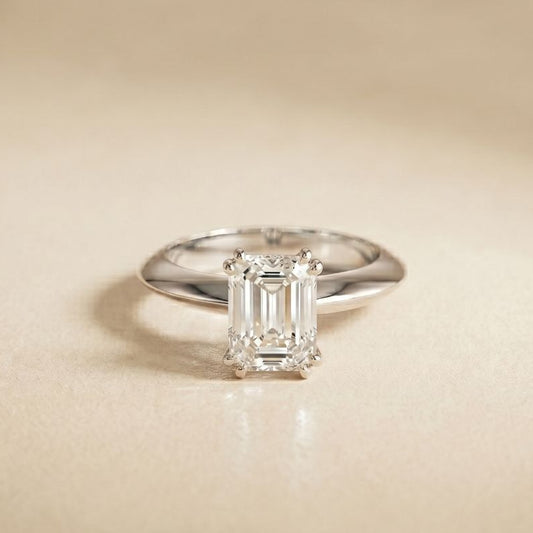 Diamond ring with emerald-cut gemstone on a beige background