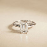 Diamond ring with emerald-cut gemstone on a beige background White