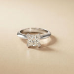 Silver ring with a diamond on a beige background White
